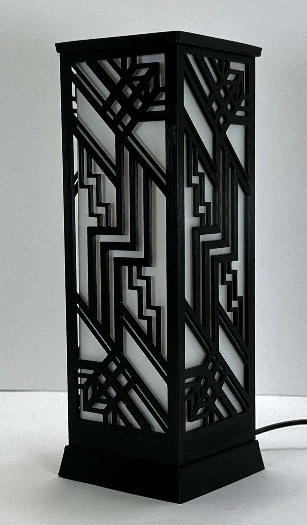 Art Deco style desktop lantern with geometric black metal frame, showcasing intricate patterns.