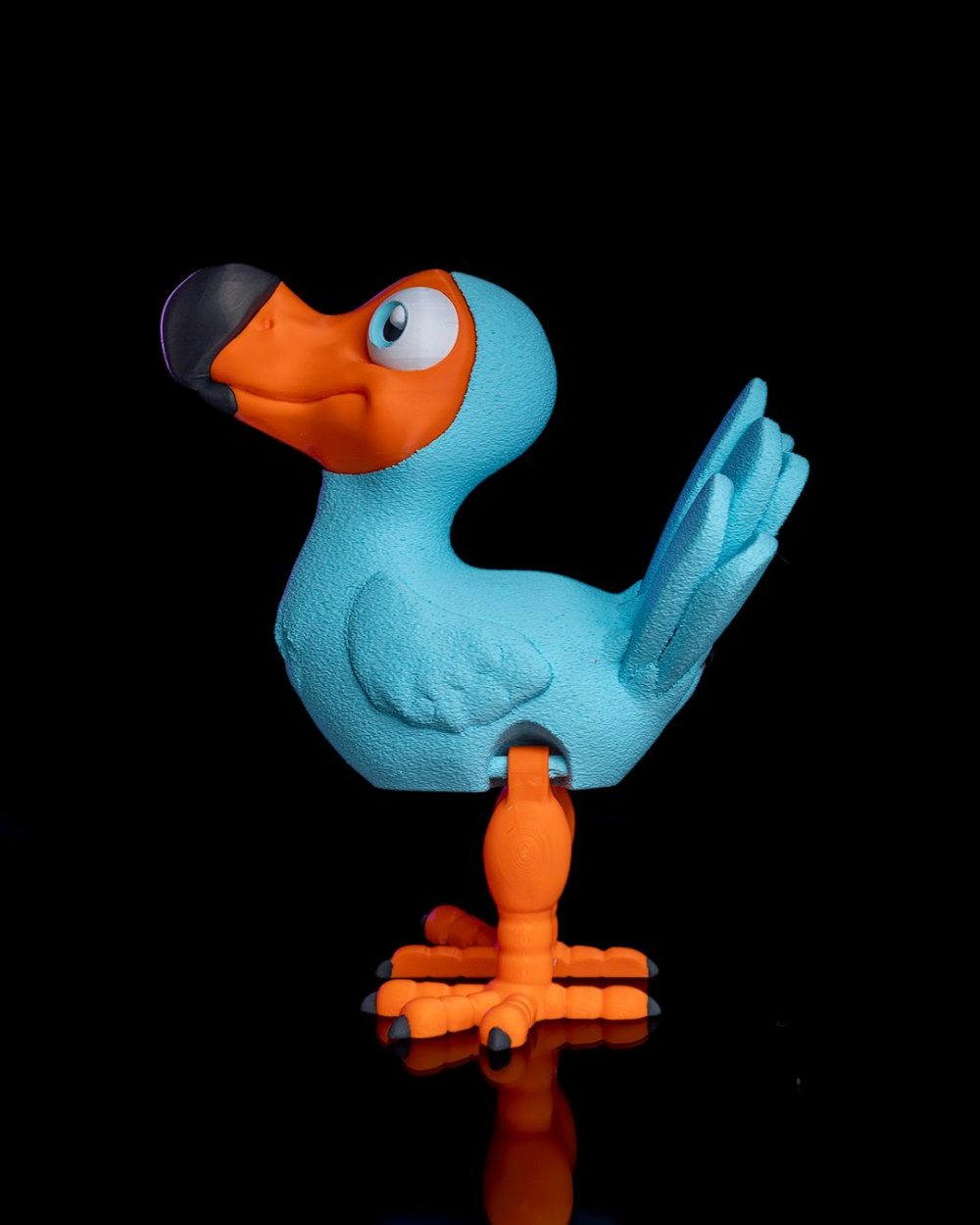 Articulated Dodo Bird – Custom – 3D Printed – Figure with blue body and orange beak, legs, standing on a reflective surface.